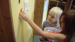 zwei Mädchen kleben einen Zickzackpfeil neben einen Lichtschalter